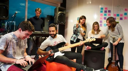 Francisco Márquez toca el bajo junto a sus compañeros de trabajo en la sala de música de Globant