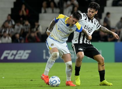 Franco Ibarra, la figura de Rosario Central, protege la pelota ante Matías Espinoza: el volante fue la guía de los canallas en Asunción