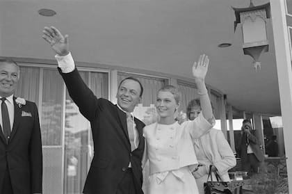 Frank Sinatra y Mia Farrow saludando a un grupo de personas que se asomaron a saludarlos luego de la ceremonia. 