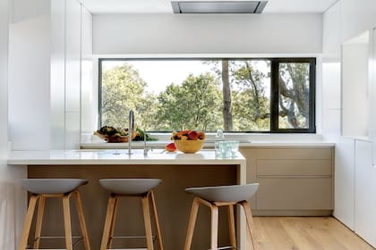 Frente a la barra de la cocina, banquetas de madera y polipropileno (Hay).