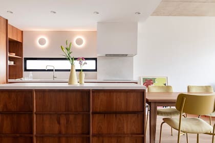 Frente a la entrada, esta cara de la isla ofrece cajones para las llaves y objetos de uso diario. Apliques circulares 'Bonwe' (Dimm).