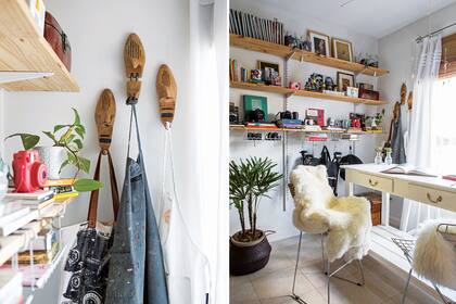 Frente a la ventana, mesa alta de madera con tapa de mármol y banquetas Bertoia (Mercado Libre). Pieles (Rancho Deco). Maceta negra de palma con palmera (paisajistas Guillermo Benítez Cruz y Paola Carotenuto). Floreros antiguos de vidrio con follaje verde (Amba
