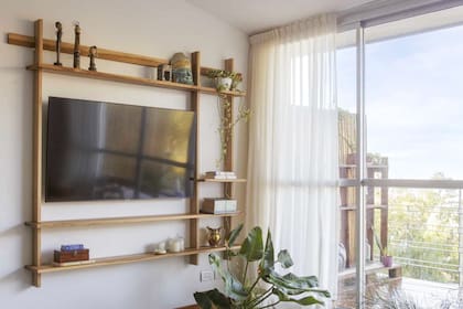 Frente al sillón, ubicaron la tele y una estantería, que ocupan poco espacio y no interfieren el paso hacia la escalera, que −sobre esa misma pared− lleva hacia la planta alta.