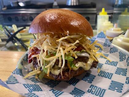 Frita Cubana lleva doble medallón de carne de vaca con carne de cerdo, queso Emmenthal, cebolla salteada con aderezo cubano, lechuga capuchina y papas paille.