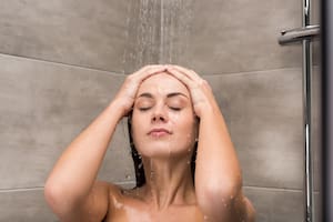 Front view of attractive woman taking shower with closed eyes