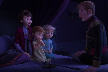 Acompañadas por su madre, la reina Iduna, las pequeñas Elsa y Anna escuchan atentamente la asombrosa historia de su padre, el rey Agnarr