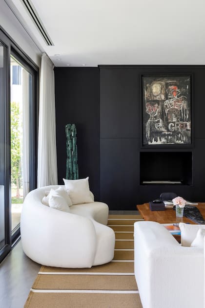 Fuera del guión convencional, la pared de chapa negra que aloja el hogar a bioetanol es un recurso moderno que, acá, también le da protagonismo al cuadro de Alberto Greco.