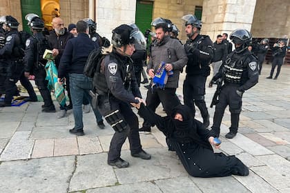 Fuerzas de seguridad israelíes desalojan a fieles musulmanes palestinos sentados en el recinto de la mezquita de Al Aqsa, en Jerusalén, a primera hora del 5 de abril de 2023, durante el mes sagrado del Ramadán