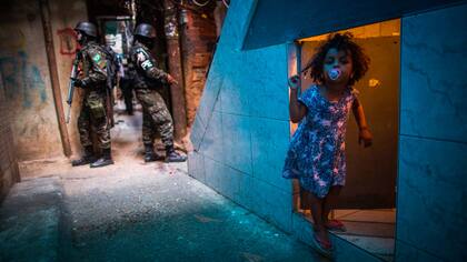Un miembro de tácticas de combate urbano, el personal de la policía militar del ejército brasileño patrulla a lo largo de un callejón en la Rocinha