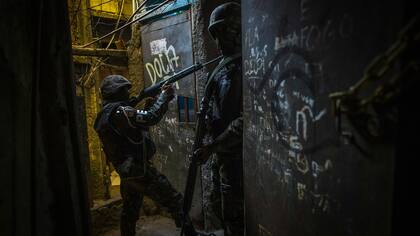 Un miembro de tácticas de combate urbano, el personal de la policía militar del ejército brasileño patrulla a lo largo de un callejón en la Rocinha