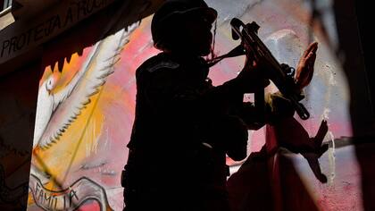 Un soldado patrulla delante de un graffiti que representa una paloma de la paz en la favela de Rocinha