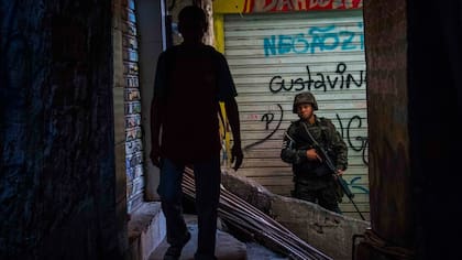 Un miembro de tácticas de combate urbano, el personal de la policía militar del ejército brasileño patrulla a lo largo de un callejón en la Rocinha