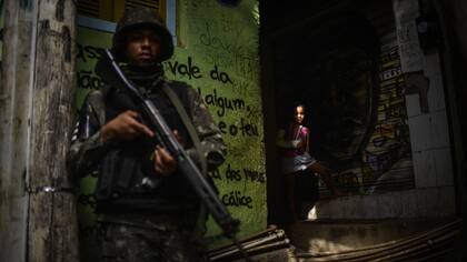 Una niña observa a un soldado fuertemente armado durante una operativo militar en la favela Rocinha