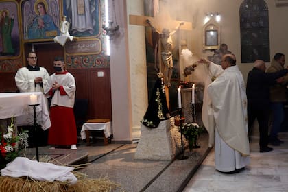 Gabriel Romanelli, párroco de la Franja de Gaza, a la izquierda, reza durante la misa del gallo en la iglesia católica de la Santa Familia en Ciudad de Gaza, el 24 de diciembre de 2021