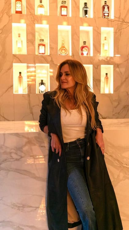 Gaby López Monzón en un rincón que ella misma diseñó: un muro iluminado que exhibe botellas como piezas de colección y transforma el bar en una experiencia sensorial.