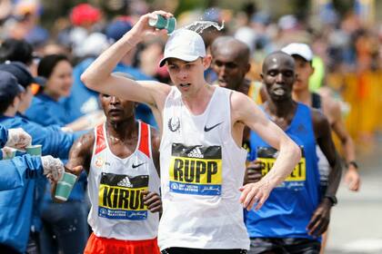 Galen Rupp en un puesto de avituallamiento; detrás Kirui
