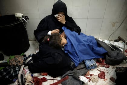 Una mujer palestina llora al lado de su pequeña hija, que resultó herida durante los bombardeos israelíes al Hospital Nasser, en la Franja de Gaza.