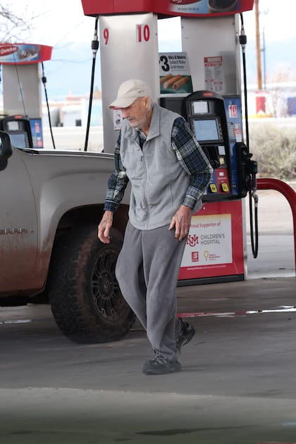 Gene Hackman sale del local de una estación de servicio en Nuevo México con un café en la mano