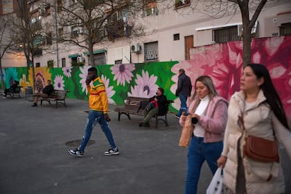 Gente camina mientras otros se sientan en bancos en una calle de L'Hospitalet de Llobregat, cerca de Barcelona