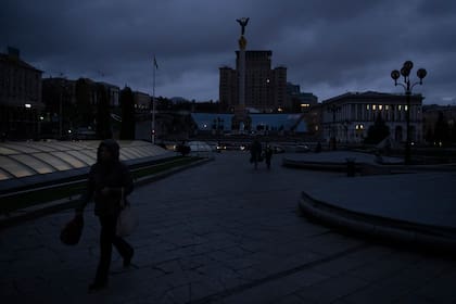 Gente caminando por la Plaza de la Independencia al anochecer en Kiev, Ucrania, el lunes 31 de octubre de 2022. Los apagones en ucrania aumentan mientras el gobierno trata de estabilizar la red energética y reparar el sistema antes del invierno. (AP Foto/Andrew Kravchenko)