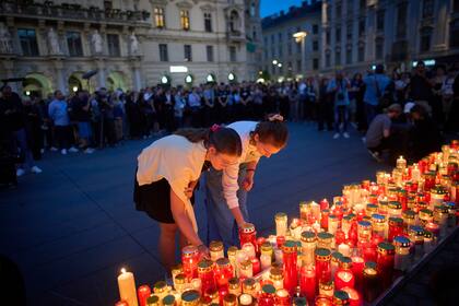 Gente enciende velas por las víctimas de un exalumno que hizo disparos en una escuela, donde mató a varias personas e hirió a muchas otras antes de suicidarse, en Graz, Austria, el martes 10 de junio de 2025. (AP Foto/Darko Bandic)