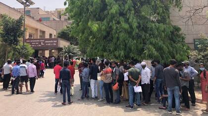 Gente esperando una prueba de covid frente a un hospital administrado por el gobierno en Noida