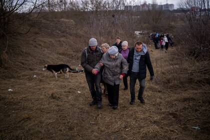 Gente huyendo de Irpin, a las afueras de Kiev, Ucrania, el lunes 7 de marzo de 2022, mientras se oye artillería cerca. Rusia ofreció un nuevo cese el fuego y un puñado de corredores humanitarios para permitir que los civiles huyeran de ciudades atacadas en Ucrania. Otras iniciativas similares anteriores han fracasado, y las fuerzas armadas rusas seguían arrojando proyectiles sobre poblaciones ucranianas. (AP Foto/Emilio Morenatti)