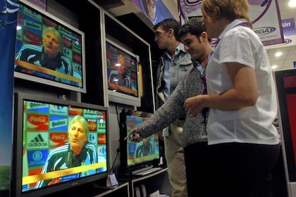 Gente mirando por televisión la nómina de los jugadores para el mundial en Alemania 2006