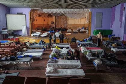 Gente sentada en camas tras ser evacuada del frente en un centro para desplazados en Pavlohrad, Ucrania, el sábado 1 de febrero de 2024. (AP Foto/Evgeniy Maloletka)