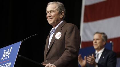 George Bush habla mientras su hermano lo observa desde atrás