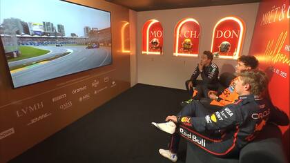 George Russell, Lando Norris y Max Verstappen descansan antes de ir al podio, mientras miran imágenes de la carrera.