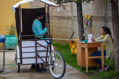 Gerardo Ixcoy le enseña fracciones a Brenda Morales, de 14 años y despliega un trapeador de esponja para servir como un recordatorio de distancia segura entre él y sus estudiantes