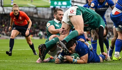 Giacomo Nicotera apoya un try para Italia ante Irlanda; de fondo, la mirada atenta de Hollie Davidson