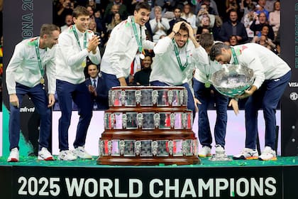 Los miembros del equipo italiano de Copa Davis reaccionan cuando Simone Bolelli deja caer la base del trofeo durante la celebración de su tercer título consecutivo en la Final de 2025 en Bolonia