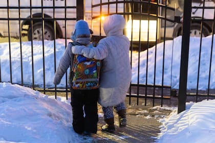Giancarlo, de 10 años, es escoltado por su madre hasta la entrada de su casa para subir al bus escolar, el 3 de febrero de 2026, en Minneapolis