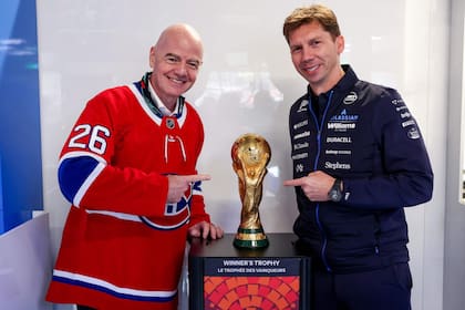 Gianni Infantino, presidente de la FIFA, junto a James Vowles, director de Williams; juntos posan con el trofeo dle Mundial, que tendrá a Canadá como una de sus tres sedes