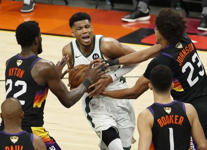 Giannis Antetokounmpo busca el aro, pero Deandre Ayton y Cameron Johnson salen a su cruce