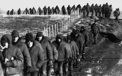 Soldados argentinos (en primer plano) son escoltados por soldados británicos después de rendirse el 2 de junio de 1982 cerca de Goose Green durante la guerra de las Islas Malvinas 