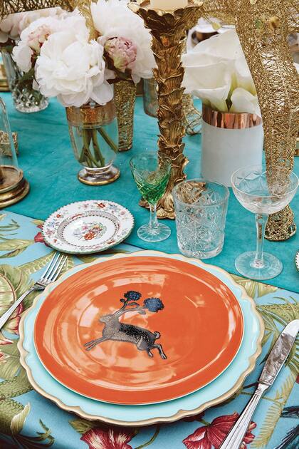 Grandes candelabros de resina dorados, floreros antiguos de cristal con peonias rosas, cubiertos de metal plateado de Plata Lappas y platos con animales de Liberty, de Londres