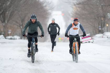 GREENVILLE, SC - JANUARY 16: People ride bicycles and run along Main St. on January 16, 2022 in Greenville, South Carolina. More than 4 inches of snow from Winter Storm Izzy has fallen with more sleet and freezing rain expected in the area for the remainder of the day.   Sean Rayford/Getty Images/AFP
== FOR NEWSPAPERS, INTERNET, TELCOS & TELEVISION USE ONLY ==