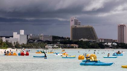 Turistas se divierten en aguas con vistas a hoteles elegantes en Tumon, un distrito turístico de la isla de Guam