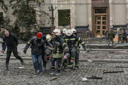 Personal del servicio de emergencia ucraniano saca el cuerpo de una víctima del edificio del ayuntamiento dañado  luego de un bombardeo en Kharkiv