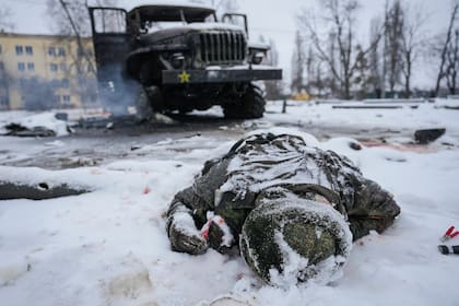 El cuerpo de un militar está cubierto de nieve junto a un vehículo lanzacohetes múltiple militar ruso destruido en las afueras de Kharkiv, Ucrania, el viernes 25 de febrero de 2022