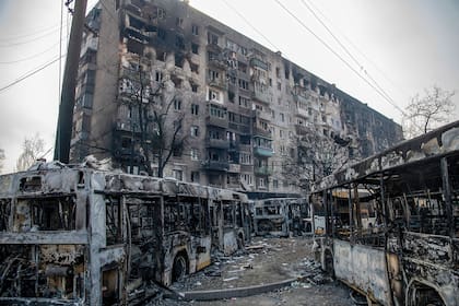 Omnibus quemados frente a un complejo residencial destruido en la ciudad ucraniana sitiada de Mariupol, 
23 de marzo de 2022