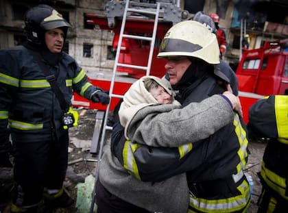 Un bombero abraza a una anciana después de ser evacuada de un edificio de apartamentos atacado por bombardeos en Kiev, Ucrania, el lunes 14 de marzo de 2022