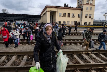 Ucranianos cruzan las vías del tren para abordar el próximo tren hacia el oeste que sale de la capital de Ucrania, Kiev, el 4 de marzo de 2022