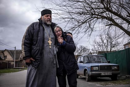 Un sacerdote consuela a una mujer que caba de perder un pariente en la aldea de Gostomel, región de Kyiv
