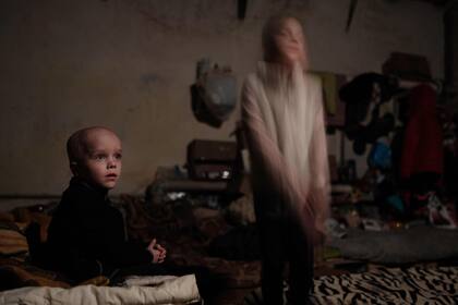 Sasha (izq.), de 4 años, y su hermana Ksenia, de 8, hijos de una familia que decidió no evacuar, posan en un dormitorio en el refugio del sótano en Lysychansk, al este de Ucrania
