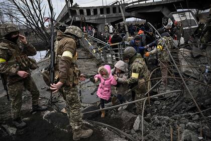 El 5 de marzo, a pocos días del comienzo de la invasión rusa, la gente cruza un puente destruido mientras evacuan la ciudad de Irpin, al noroeste de Kyiv, durante fuertes bombardeos