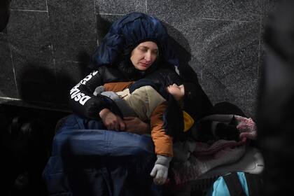 Una madre observa a su hijo dormir en la estación de tren de Lviv, en el oeste de Ucrania, mientras espera para poder abandonar la zona de conflicto